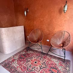 Sala de descanso do Kura com tapete e parede terracota