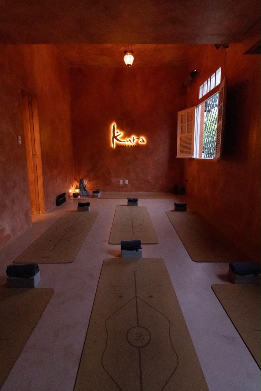 Sala terracota do Kura com tapetes de cortiça e logotipo iluminado
